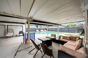 Eine Außenpatio mit Pool, Liegestühlen und einer überdachten Sitzgruppe.