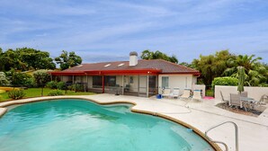 Ein Haus mit Swimmingpool, Terrasse mit Stühlen und Garten.
