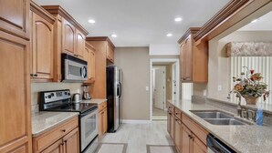 A kitchen with wooden cabinets, stainless steel appliances, granite countertops, and a backsplash. - Snowbird friendly elegant home with waterfront location pool grill fireplace (Largo)