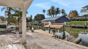 A marina with boats docked, a covered area with benches, and palm trees in the background. - Snowbird friendly elegant home with waterfront location pool grill fireplace (Largo)