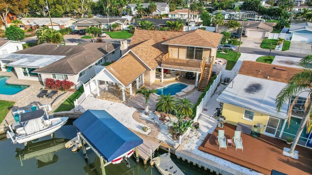 A residential area with a house featuring a large deck, a swimming pool, and a boat dock. - Snowbird friendly elegant home with waterfront location pool grill fireplace (Largo)