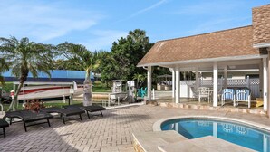 A pool area with lounge chairs, a covered patio, and a boat trailer in the background. - Snowbird friendly elegant home with waterfront location pool grill fireplace (Largo)