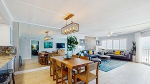 A spacious living area with a wooden dining table, a sofa, and a large window. - Spacious cottage with glorious Gulf view and beachfront heated pool and spa (Indian Shores)