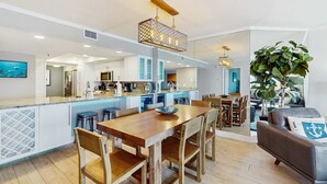 A modern kitchen with white cabinets, a wooden dining table, and a hanging light fixture. - Spacious cottage with glorious Gulf view and beachfront heated pool and spa (Indian Shores)