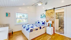 A bedroom with a bed, bedside table, and a sliding door leading to a bathroom. - Beautiful Estate on Millers Bayou with Free WiFi Game Room Firepit and Hammock (Port Richey)