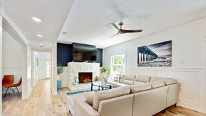 A spacious living room with a large beige sectional sofa, a fireplace, and a ceiling fan. - Beautiful Estate on Millers Bayou with Free WiFi Game Room Firepit and Hammock (Port Richey)