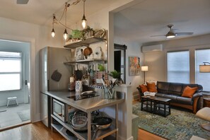 Eine moderne Küche mit Edelstahlgeräten, eine Essecke mit einer Ledersofa und ein Wohnzimmer mit einem gemusterten Teppich.