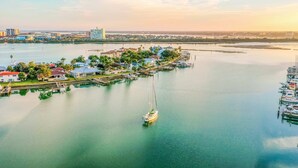 A marina with a sailboat, docked boats, and a waterfront property with houses and greenery. - Waterfront Condo w WiFi Washer Dryer and Central AC Snowbird Friendly (Clearwater Beach)