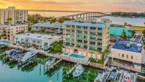 A marina with boats docked, a building with multiple balconies, and a bridge in the background. - Waterfront Condo w WiFi Washer Dryer and Central AC Snowbird Friendly (Clearwater Beach)