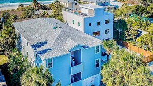 A multi-story building with a flat roof, located near a beach with palm trees and ocean views. - Gulf view and stunning sunsets family friendly steps from beaches WD and WIFI (Indian Rocks Beach)