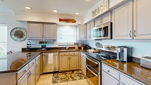 A kitchen with white cabinets, a stainless steel microwave, an oven, and a coffee maker. - Gulf view and stunning sunsets family friendly steps from beaches WD and WIFI (Indian Rocks Beach)
