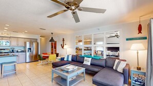 A modern living room with a sofa, coffee table, and a ceiling fan. - Gulf view and stunning sunsets family friendly steps from beaches WD and WIFI (Indian Rocks Beach)