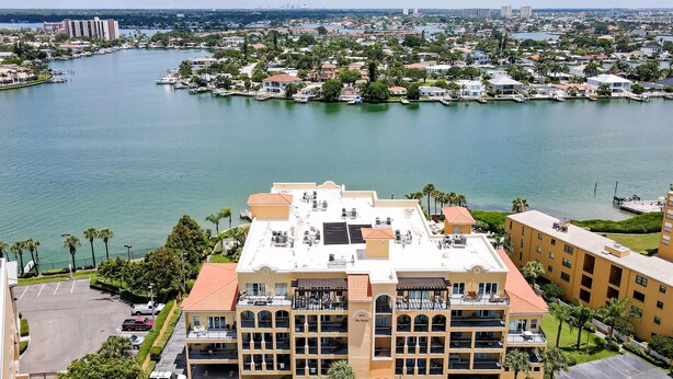 A hotel with multiple balconies, a parking lot, and a view of a marina and cityscape. - Water view condo with pool hot tub pier private balcony AC and washer dryer (Treasure Island)