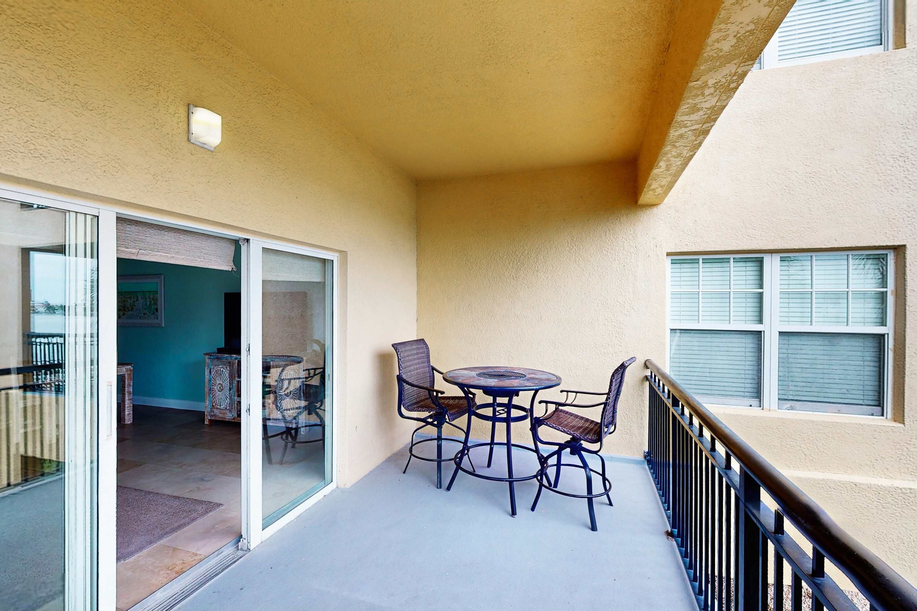 Un balcon avec une table et des chaises, une porte-fenêtre coulissante et une vue sur l’intérieur.