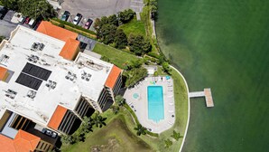 An aerial view of a hotel with a swimming pool, a dock, and a parking area. - Water view condo with pool hot tub pier private balcony AC and washer dryer (Treasure Island)