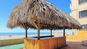 A beachside area with a thatched structure, a wooden bench, and a view of the sea.