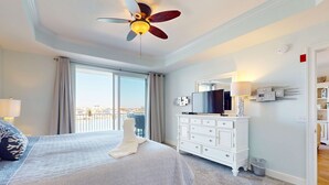Quarto com cama, penteadeira, televisão e vista para a cidade.