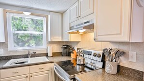 A kitchen with white cabinets, a stainless steel range hood, a built-in oven, and a granite countertop. - Quiet Waves 20 Condo with Pool Steps to Dining Shopping and St Pete Beach (St. Pete Beach)