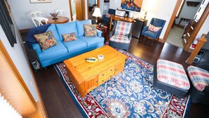 A living room with a blue sofa, a wooden coffee table, and patterned rugs.