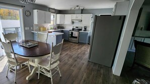 Une cuisine de taille réduite avec des meubles blancs, une table à manger avec des chaises et un réfrigérateur.
