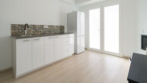 Una cocina moderna con armarios blancos, salpicadero estampado y refrigerador empotrado.