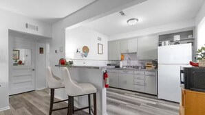 A modern kitchen with white cabinetry, a bar stool, and a built-in oven.
