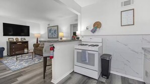 A modern kitchen with a gas stove, white cabinets, and a marble backsplash.