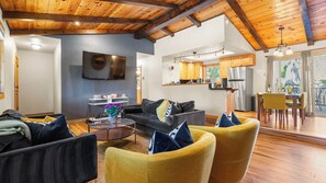 A modern living room with a sofa, armchairs, a coffee table, and a TV. There is a kitchen area with a refrigerator and a dining table with chairs. - Steps to Trails & Minutes to Heavenly + Fireplace + Deck + BBQ Bluewood Cabin by Avantstay (South Lake Tahoe)