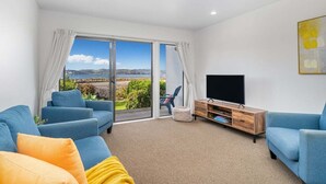 Ein modernes Wohnzimmer mit einem großen Schiebeglasfenster, das auf einen Balkon mit einem schönen Ausblick führt.