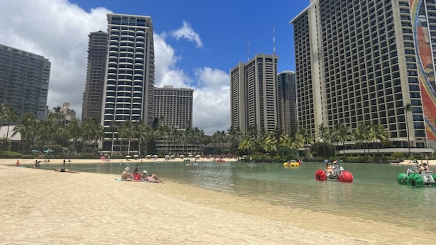 Un hotel sulla spiaggia con alti edifici, una spiaggia sabbiosa e attività acquatiche.