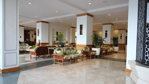 Un'ampia hall con diverse zone relax, inclusi divani e poltrone, e un pavimento piastrellato.