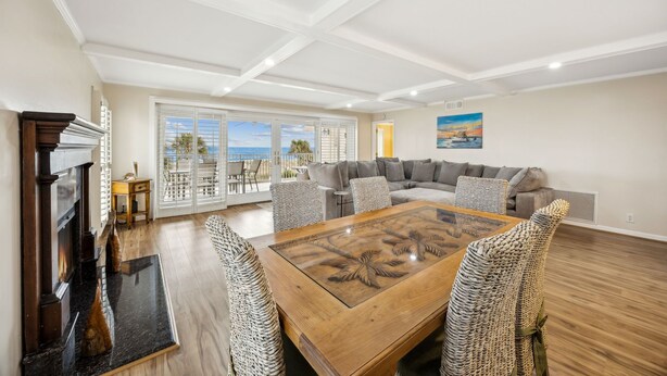 A spacious living room with a fireplace, a large wooden coffee table, and a view of the ocean through large sliding doors.