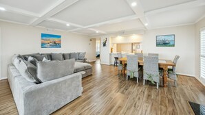 A modern living room with a grey sofa, wooden dining table with chairs, and artwork on the walls.