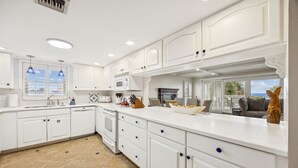 A modern kitchen with white cabinetry, a large island, and a view of the outdoors.