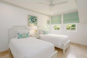 A bedroom with two beds, a ceiling fan, and a window with green blinds.