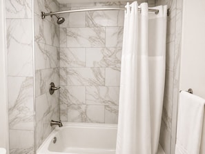 A bathroom with a shower, marble tiles, a bathtub, and a towel rack. - Torraille Waterfall Villas (Soufrière)