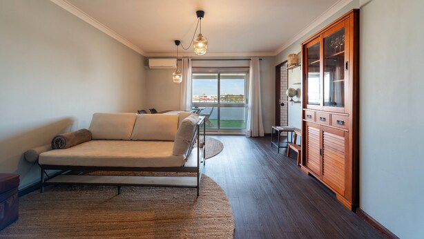A modern living room with a sofa, a wooden cabinet, and a view through a large window. - The Porto Wine Cellars Penthouse (Vila Nova de Gaia)