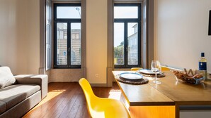 Ein modernes Wohnzimmer mit einer Couch, einem Esstisch mit Stühlen und Blick durch große Fenster.
