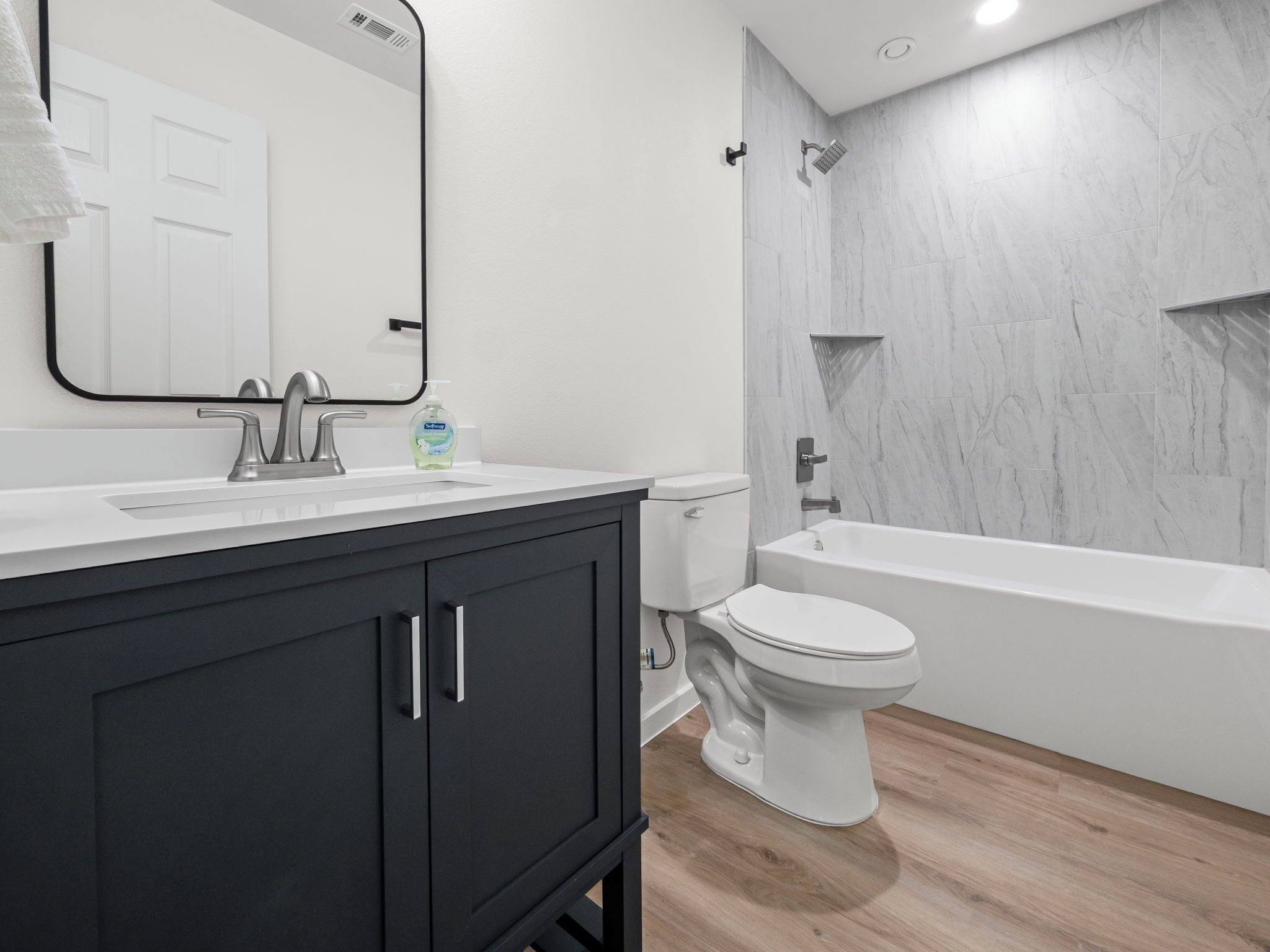 Une salle de bain moderne avec un lavabo blanc, des meubles noirs, des toilettes et une baignoire.