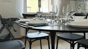 A dining table set with plates, glasses, and cutlery in a modern kitchen with a view of buildings outside. - Mercuzio’s Dream - With 5 Rooms near the Arena (Verona)