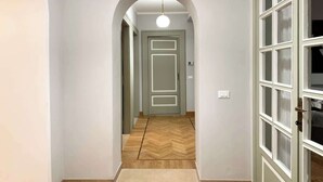A hallway with a herringbone-patterned floor, a door with frosted glass panels, and a pendant light. - Mercuzio’s Dream - With 5 Rooms near the Arena (Verona)