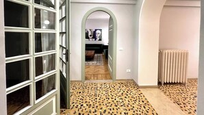 A hallway with a patterned floor, a radiator, and a door leading to a room with a painting. - Mercuzio’s Dream - With 5 Rooms near the Arena (Verona)