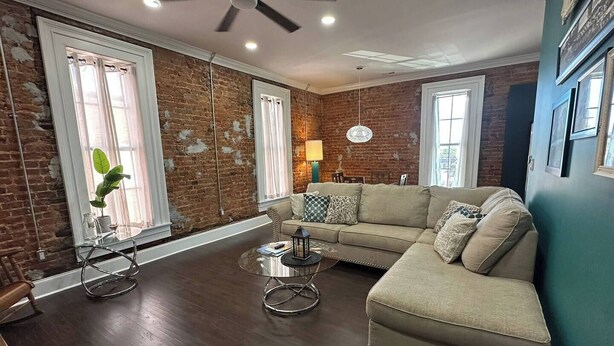A living room with a brick wall, a ceiling fan, a sofa, and a coffee table.