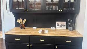 A kitchen with a black cabinet and wooden countertop.