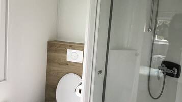 Ein modernes Badezimmer mit Toilette, einer Wand aus Holzpaneelen und einer Duschkabine aus Glas.