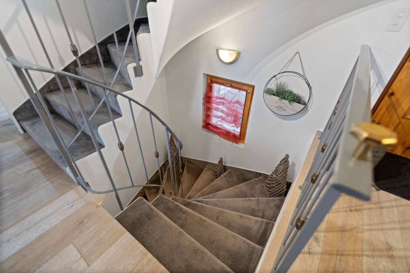 Un escalier avec une rampe en métal, des marches recouvertes de moquette et une main courante en bois.