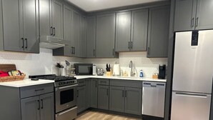 A modern kitchen with grey cabinets, stainless steel appliances, and a wooden floor. - New Cozy Fully Furnished Studio Lone Tree (Lone Tree)
