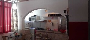 Une cuisine compacte équipée d’un four à micro-ondes, d’une cuisinière et d’un réfrigérateur. Un petit coin repas avec une table et des chaises est également disponible.