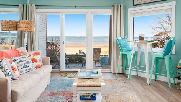 Ein Wohnzimmer mit einer Couch, einem Couchtisch und Blick auf den Strand.
