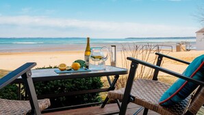 Une table avec une bouteille, un pichet et des citrons, placée sur une terrasse donnant sur une plage.